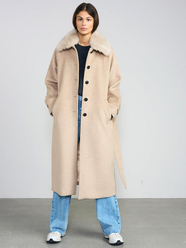 A model wearing a beige coat with a fur collar, paired with blue jeans and sneakers, showcasing MEOTINE's stylish outerwear.