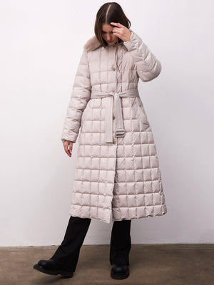 A woman models a light beige quilted coat with a belted waist, featuring a fur collar, by MEOTINE, set against a plain background.