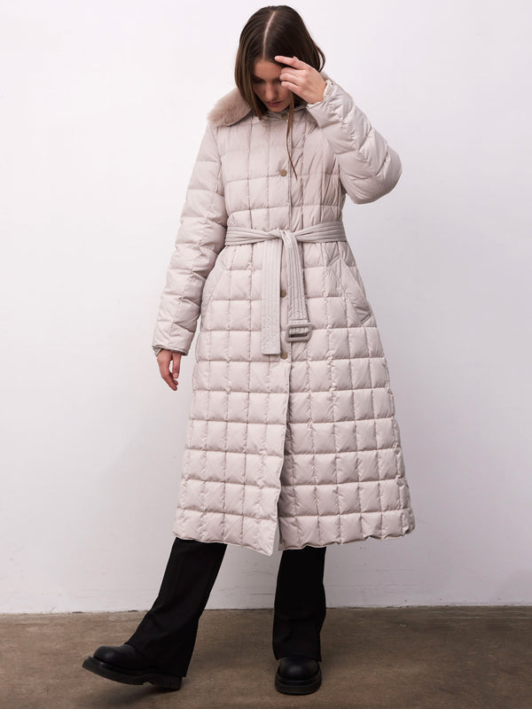 A woman models a light beige quilted coat with a belted waist, featuring a fur collar, by MEOTINE, set against a plain background.