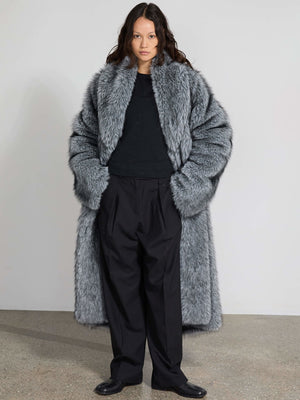 A model showcases a luxurious gray faux fur coat by MEOTINE, paired with black trousers, exuding elegance and warmth.