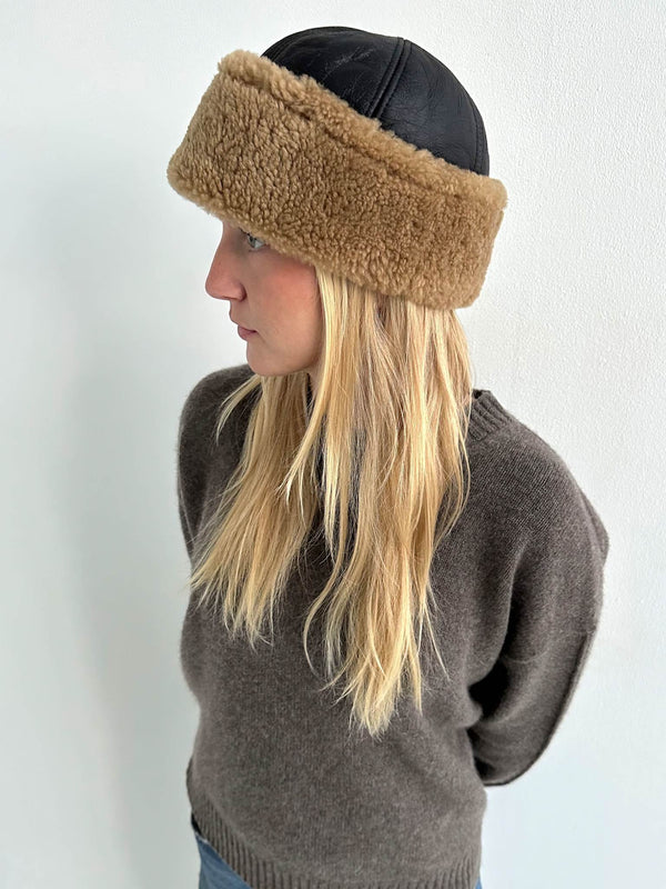 A woman with long blonde hair wears a stylish MEOTINE hat featuring a black leather top and a fluffy brown band.