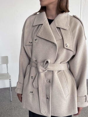 A model showcases a stylish beige double-breasted coat with a belt, perfect for a chic look by MEOTINE.