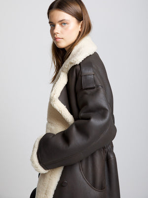A model showcases a stylish brown shearling coat with a cozy white lining, embodying the chic essence of MEOTINE.
