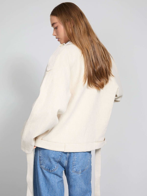 A model showcases a cream-colored oversized jacket with long sleeves, paired with light blue jeans, representing MEOTINE's style.