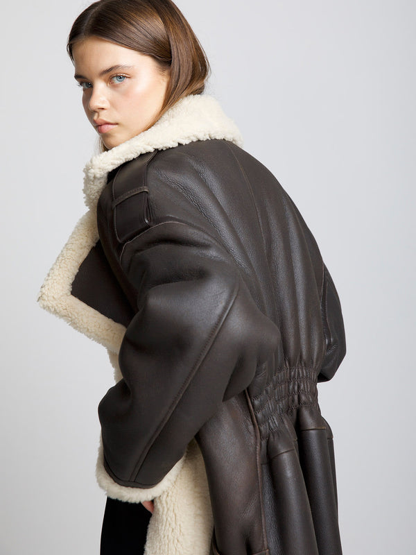 A model showcases a stylish brown shearling coat with a cozy collar, embodying the chic essence of MEOTINE fashion.