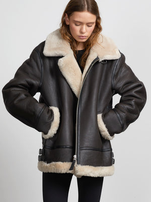 A stylish black shearling jacket with a cozy cream collar and cuffs, perfect for a chic winter look by MEOTINE.
