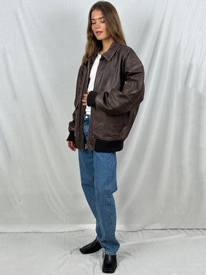 A model showcases a stylish brown leather jacket from MEOTINE, paired with a white shirt and blue jeans, exuding a casual vibe.