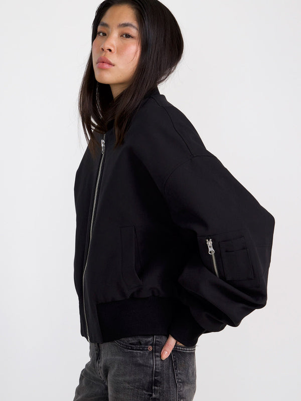 A model showcases a stylish black bomber jacket with a zippered front and oversized sleeves, embodying MEOTINE's modern aesthetic.