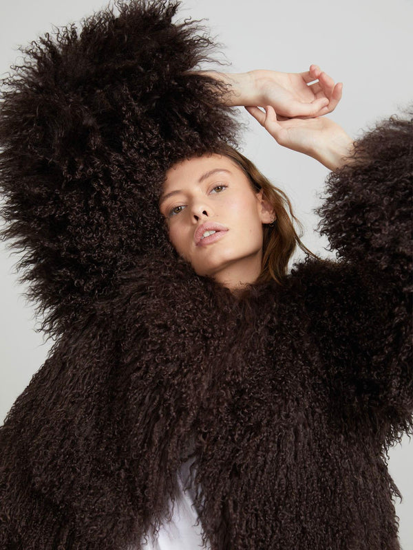 A model poses in a fluffy, dark brown MEOTINE coat, showcasing its textured sleeves and stylish silhouette against a neutral background.