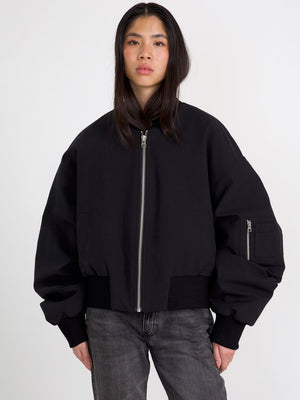 A model wears a stylish black bomber jacket with a zip front and oversized sleeves, showcasing MEOTINE's modern design.