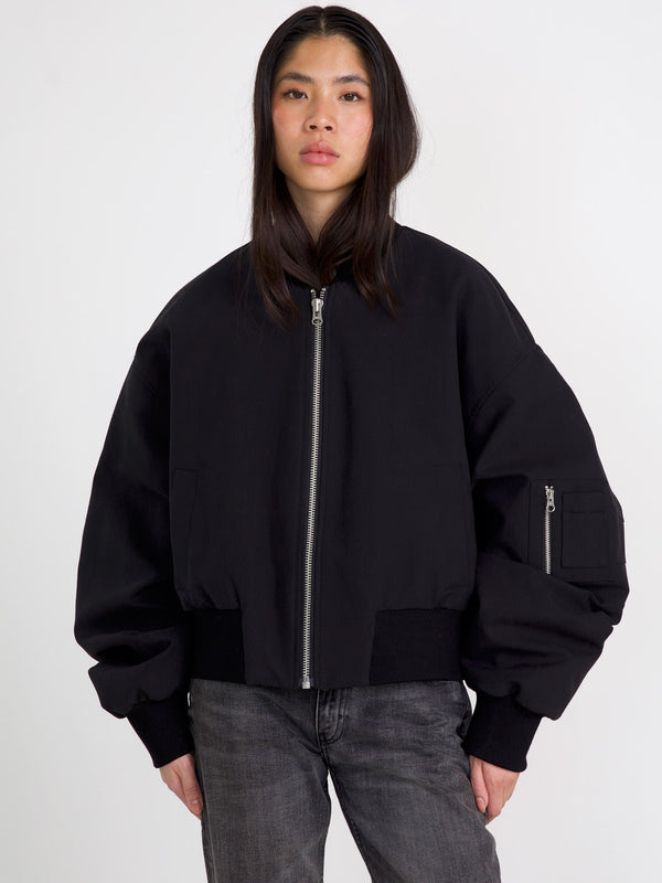A model wears a stylish black bomber jacket with a zip front and oversized sleeves, showcasing MEOTINE's modern design.