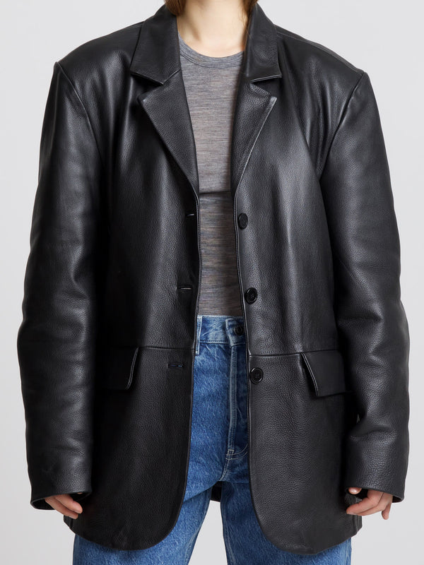 A stylish oversized black leather blazer from MEOTINE, paired with a casual gray top and high-waisted blue jeans.
