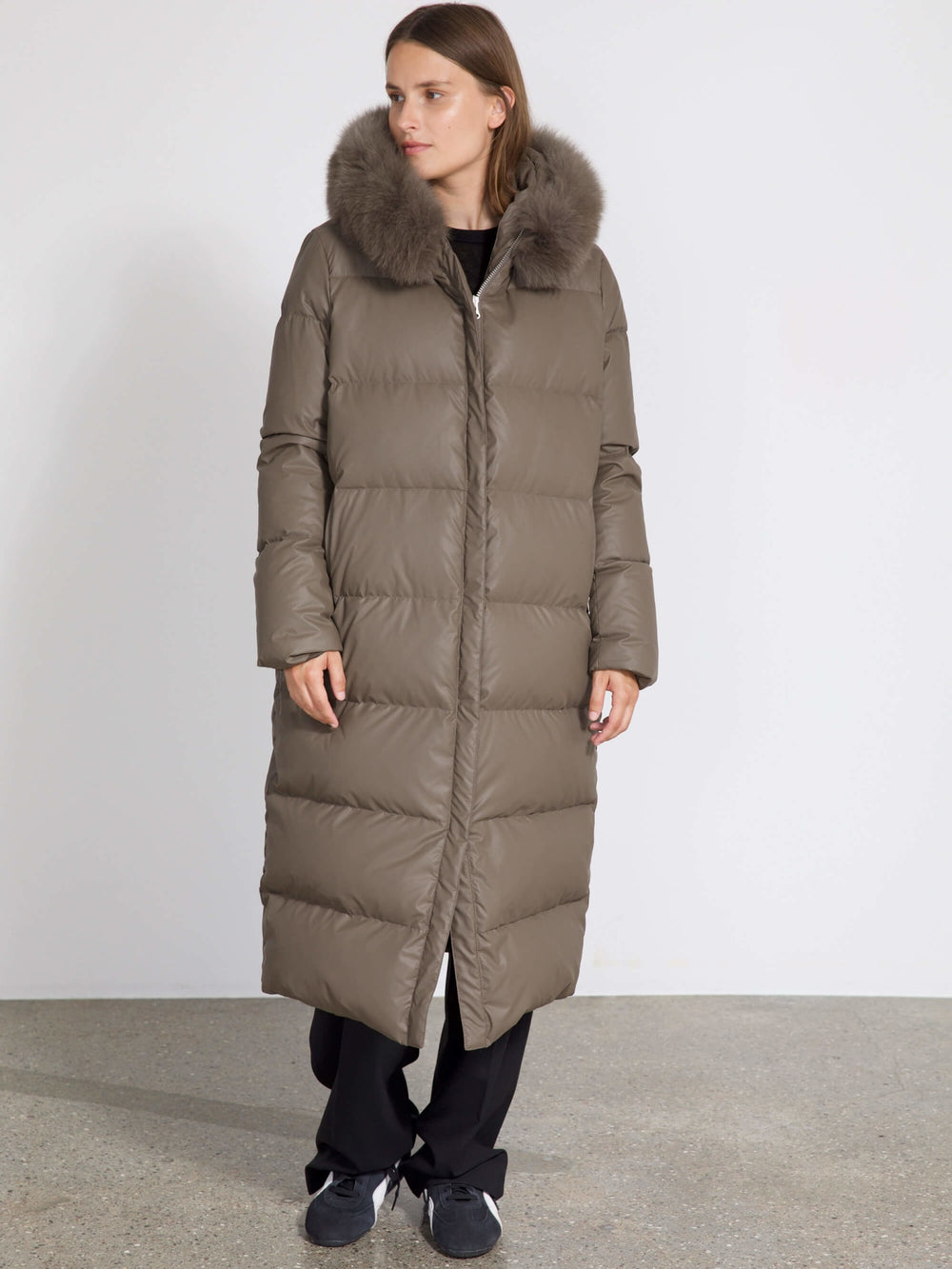 A woman models a long, olive green puffer coat with a fur-lined hood, showcasing MEOTINE's stylish winter outerwear.